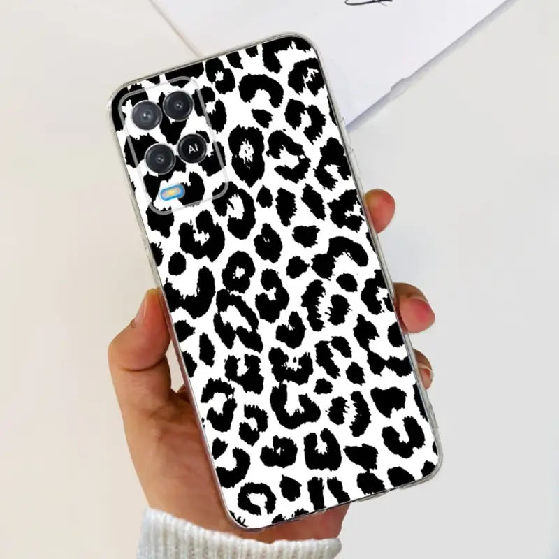 a woman holding a phone case with a black and white leopard print