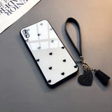 a black and white phone case with a heart charm