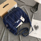 a blue denim backpack with a white box and a black and white striped bag