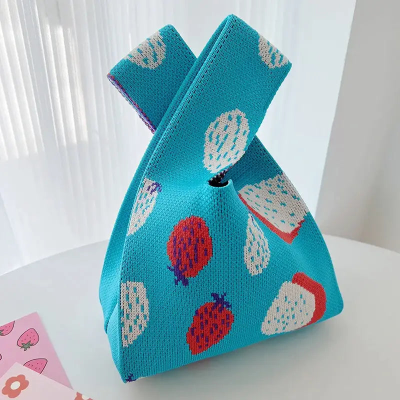 a blue knitted bag with a strawberry pattern on it