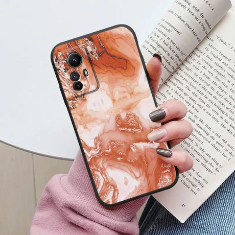 Someone holding a book and a phone case with a marble design