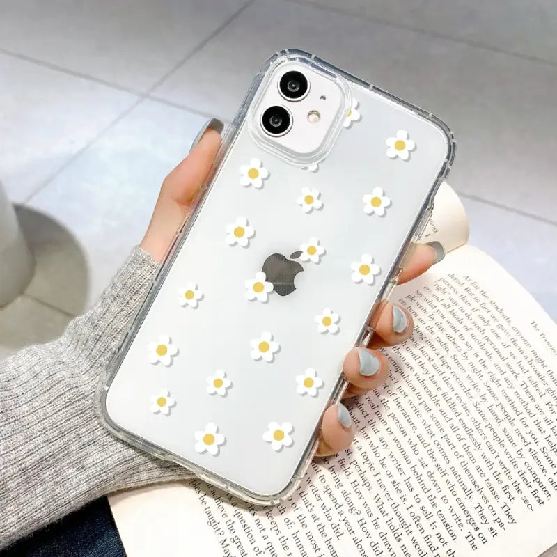 someone holding a book with a white flower case on it