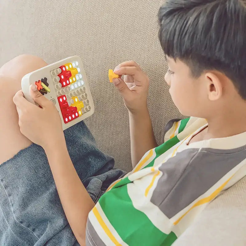 a boy sitting on a couch playing with a toy