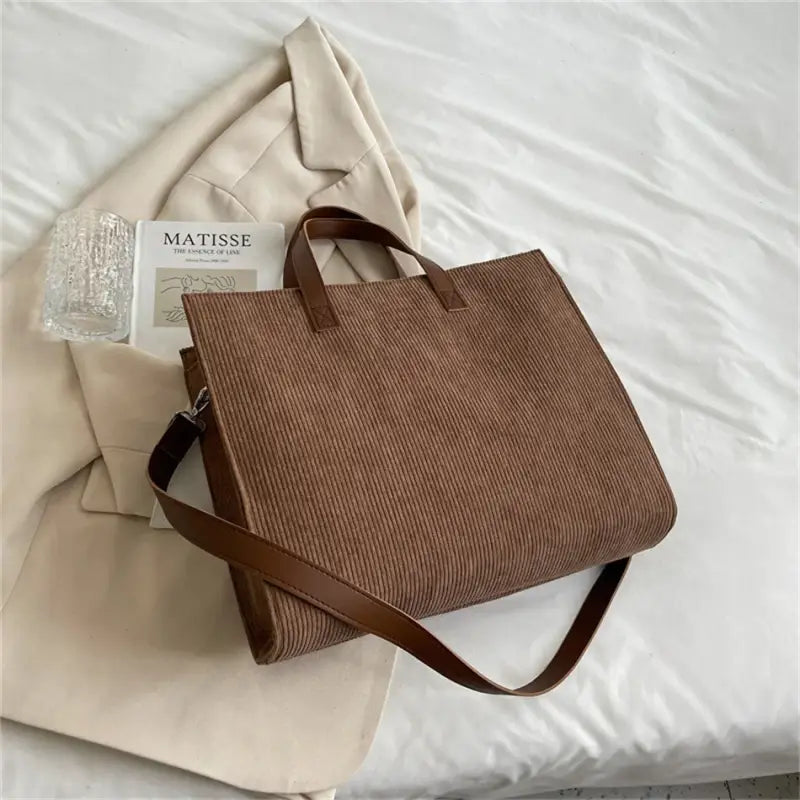 a brown bag sitting on top of a bed