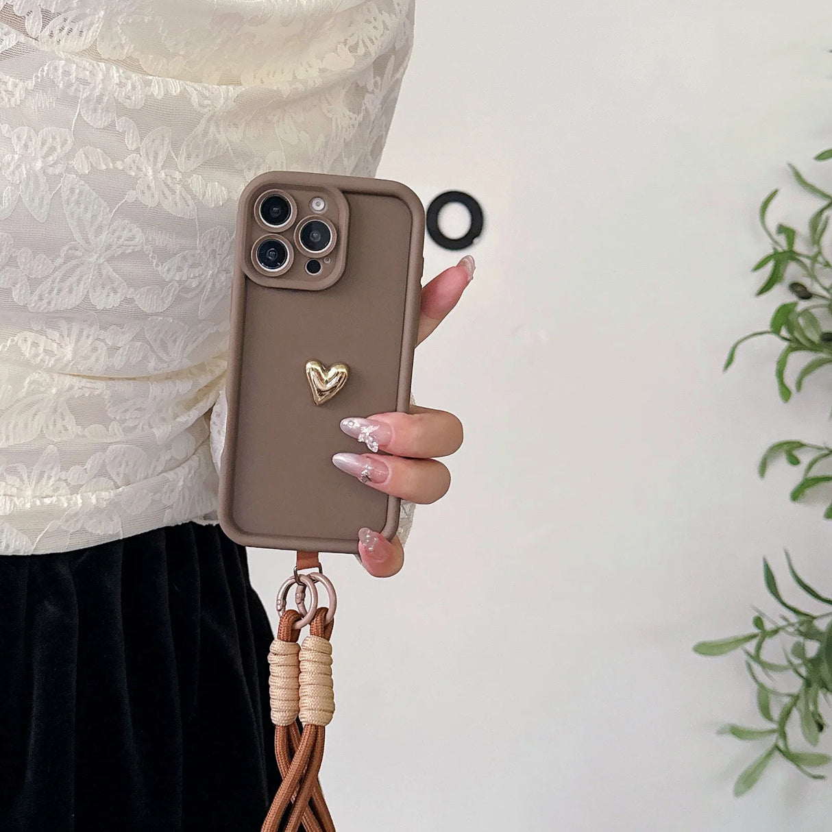 Brown phone case with heart charm and lanyard.