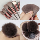 a close up of a person holding a bunch of makeup brushes