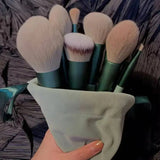 a person holding a bunch of makeup brushes