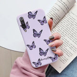 a woman holding a purple phone case with butterflies on it