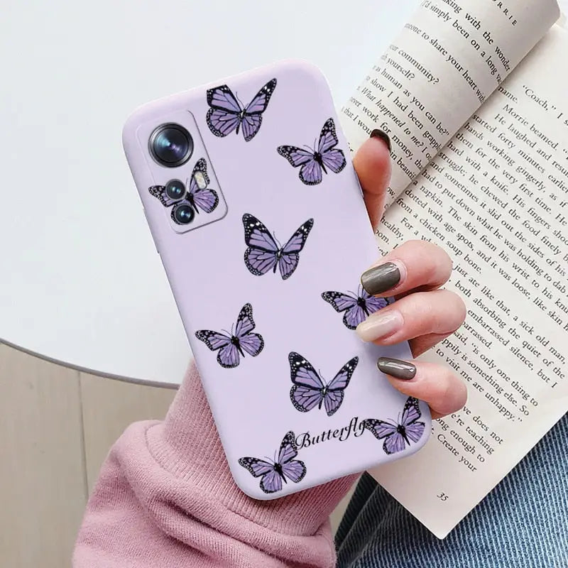 a woman holding a purple phone case with butterflies on it