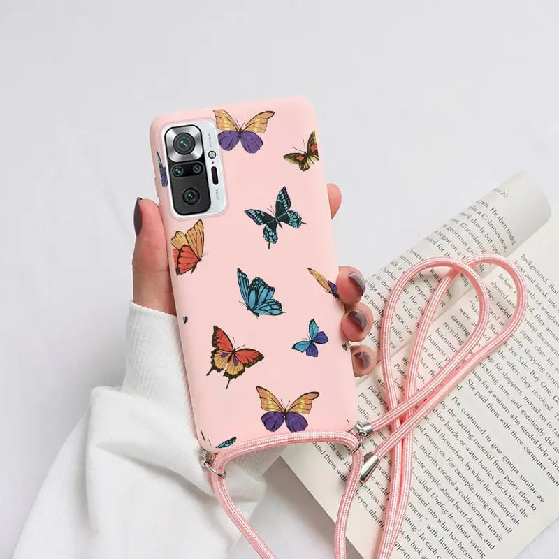 a woman holding a pink phone case with butterflies on it