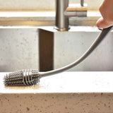 a hand holding a metal brush over a sink