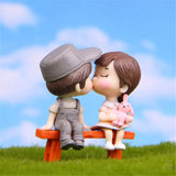a couple kissing on a bench in the grass