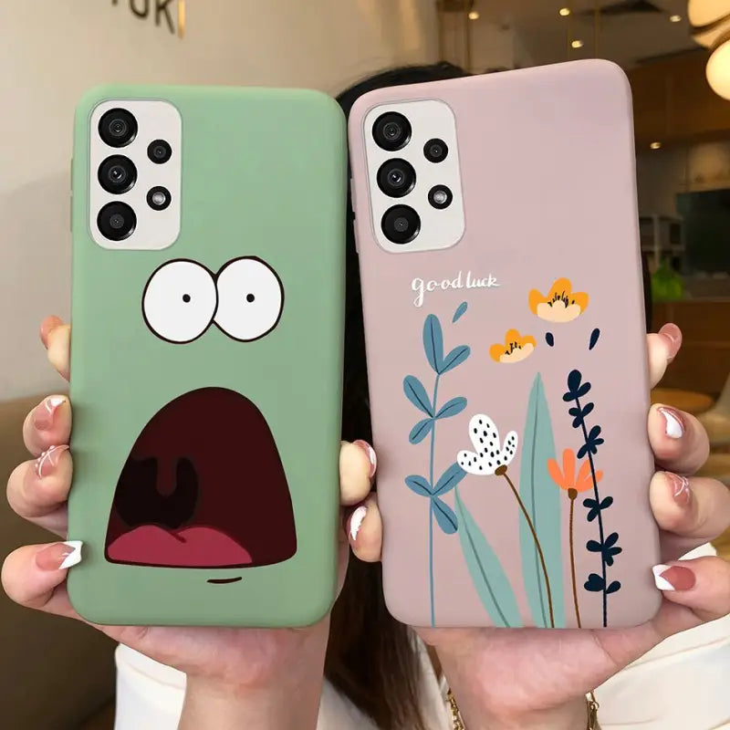 two people holding up their phone cases with cartoon faces