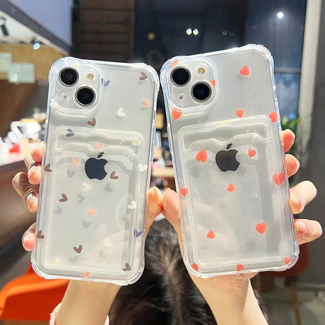 a woman holding two iphone cases with hearts on them