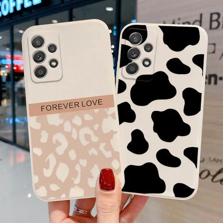 a woman holding a phone case with a cow print