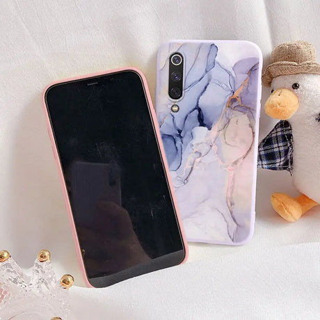 a phone case with a marble pattern and a teddy bear