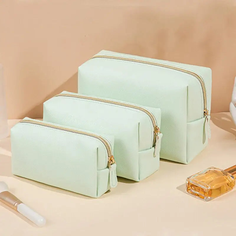 three pieces of green makeup bags sitting on a counter