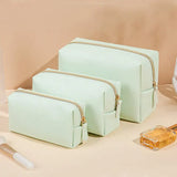 three pieces of green makeup bags sitting on a counter