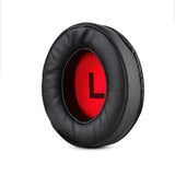 Circular black leather ear cushion with a red interior displaying the letter ’L’.