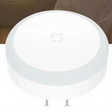 Circular white smart home device or sensor with a subtle logo on top.