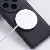 Circular white wireless charging pad attached to a black smartphone case.