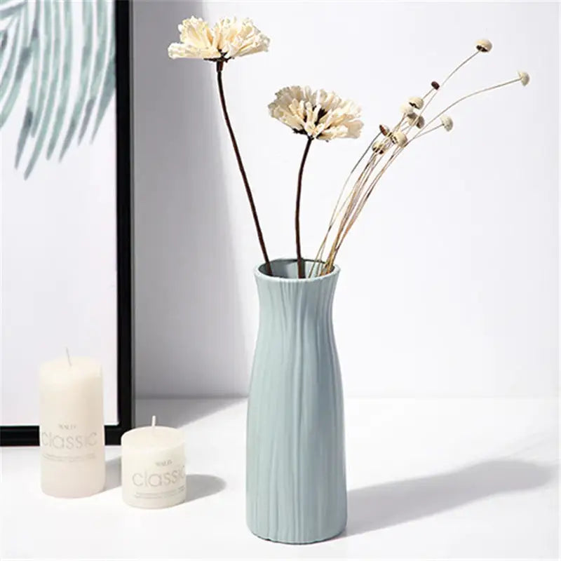 a vase with flowers in it next to a candle