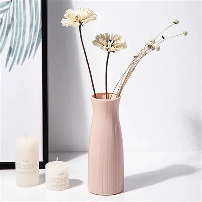 a vase with flowers in it next to a candle