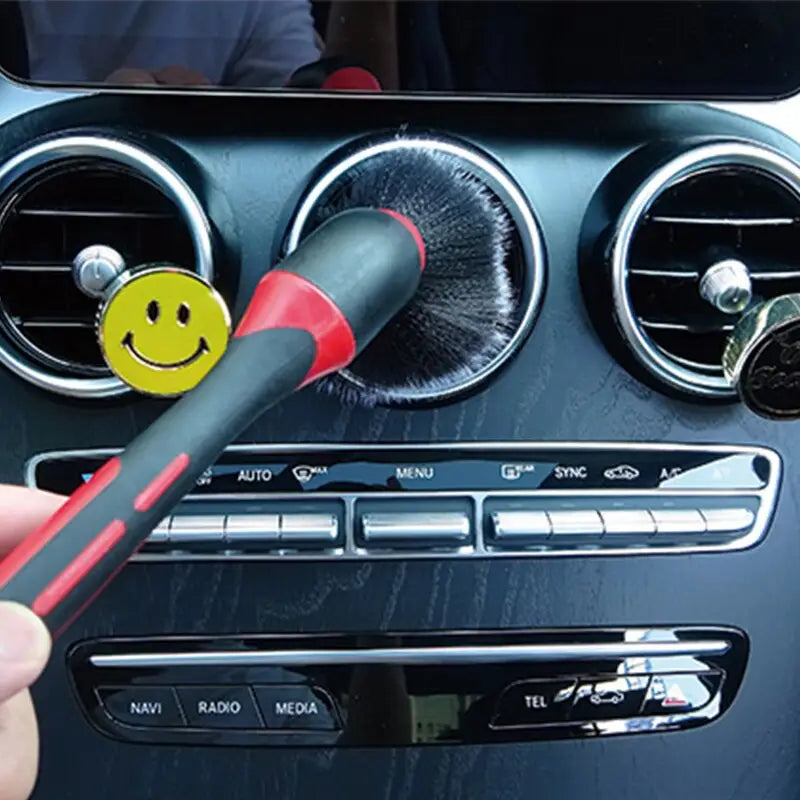 a person cleaning a car dashboard with a brush