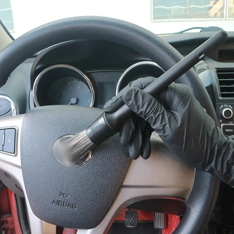 a person in black gloves cleaning a car