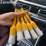 a close up of a person holding a bunch of brushes in a car