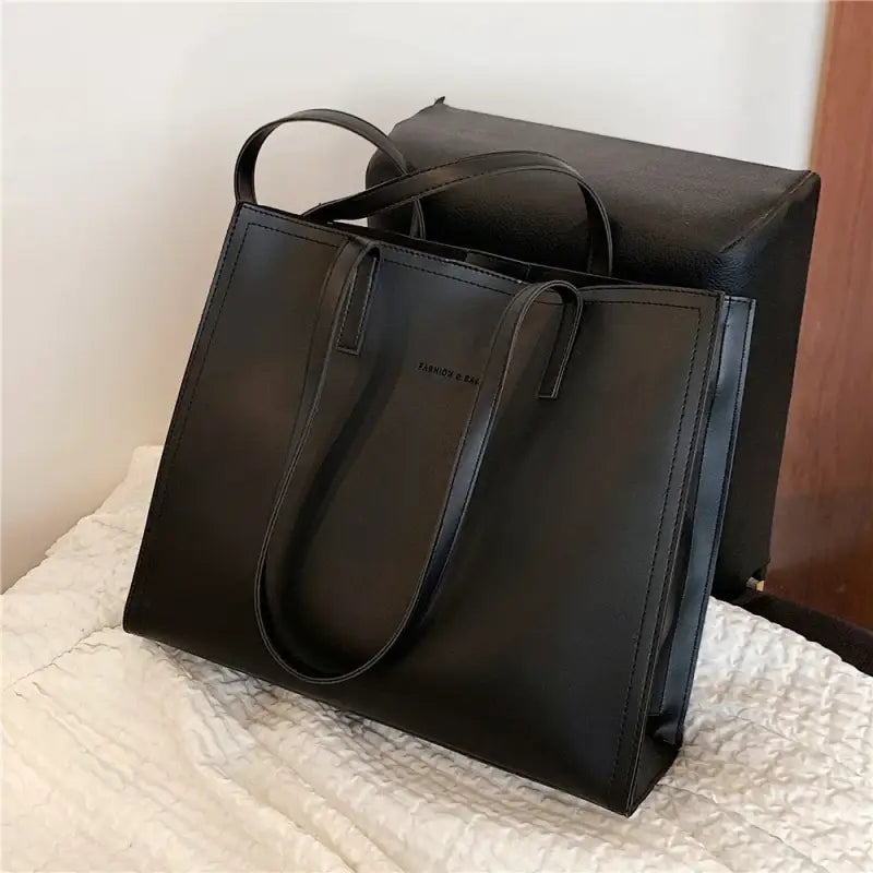 a close up of a black bag on a bed with a white blanket