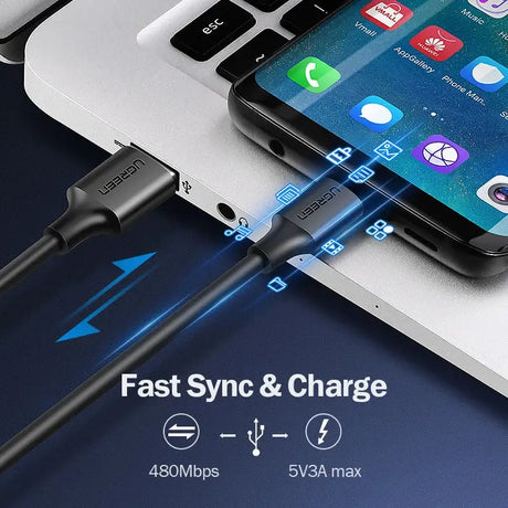 A close up of a cell phone charging on a laptop