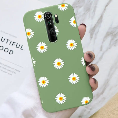 A close up of a person holding a green phone case with daisies on it