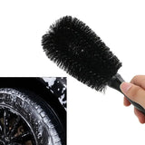 a close up of a person holding a brush in front of a tire
