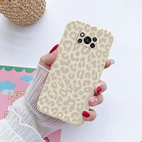 a woman holding a phone case with a leopard print