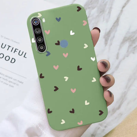 a woman holding a green phone case with hearts on it