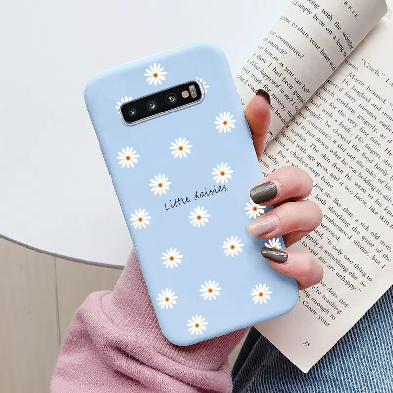 a close up of a person holding a phone case with daisies on it