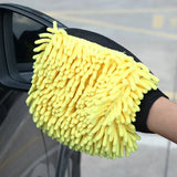 a close up of a person holding a yellow glove over a car