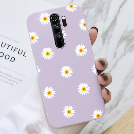 A close up of a person holding a purple phone case with daisies on it