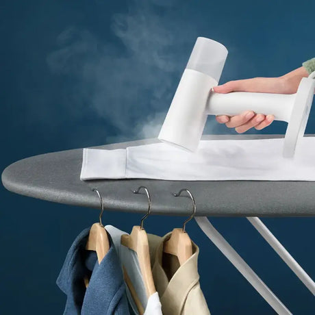 Someone ironing clothes on a ironing board with a steam