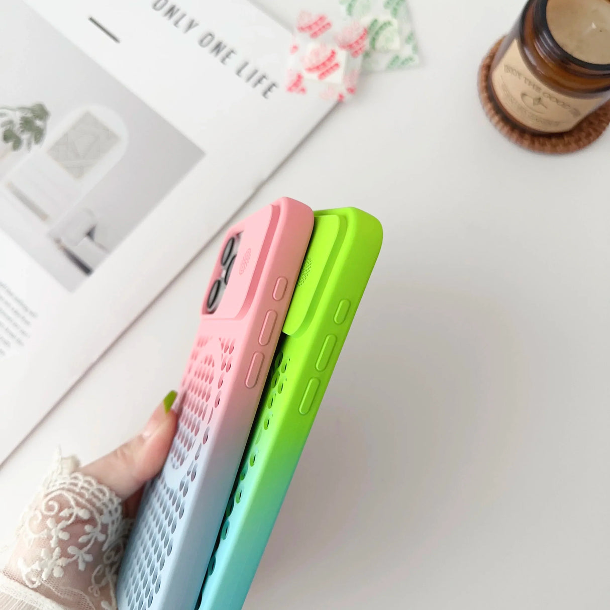 Colorful smartphone cases held in a hand with lace sleeve.