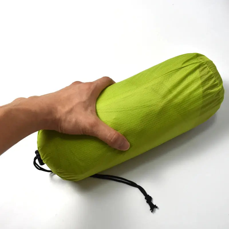 a hand holding a green bag with a black string