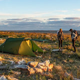 two people standing next to a tent on a rocky hill