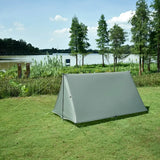a tent is pitched on the grass by the water