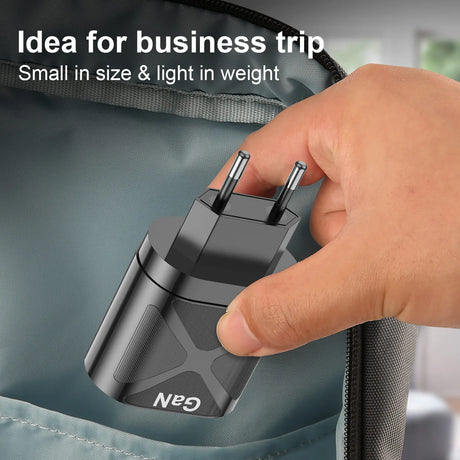 Compact black electrical adapter or charger being held by a hand.