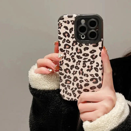 a woman holding a phone case with a leopard print