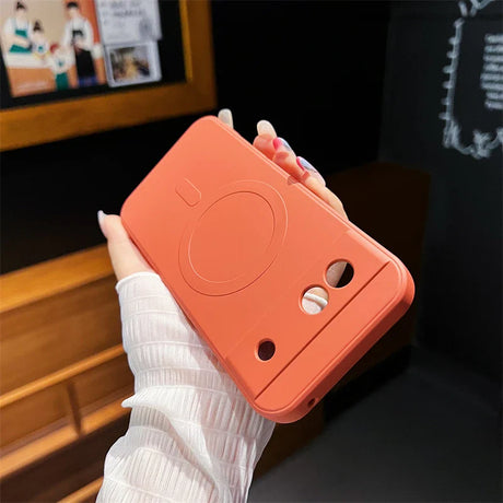 Coral-colored instant camera with a minimalist design.