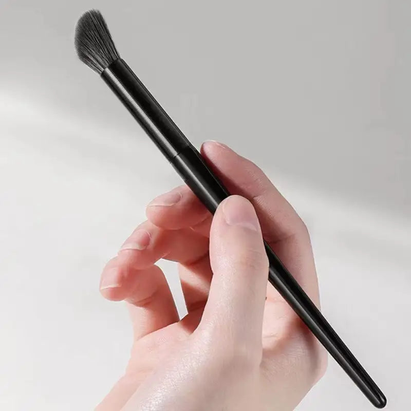 a hand holding a black brush