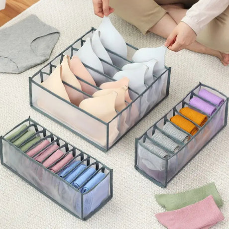 a woman sitting on the floor with three clear boxes filled with folded paper