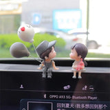 a couple of cute cartoon dolls sitting on the dashboard of a car